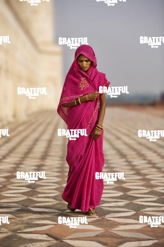 woman in red walking by the taj mahal