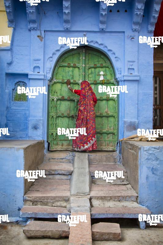 Woman knocking on door in the Blue City of Jodphur, India