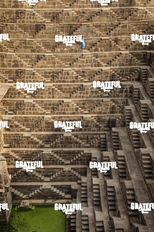 Woman with blue Sari walking to get water in the Chand Baori Step Well in India 2