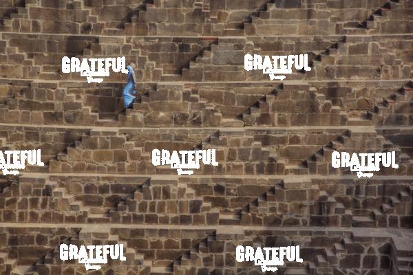Woman with blue Sari walking to get water in the Chand Baori Step Well in India