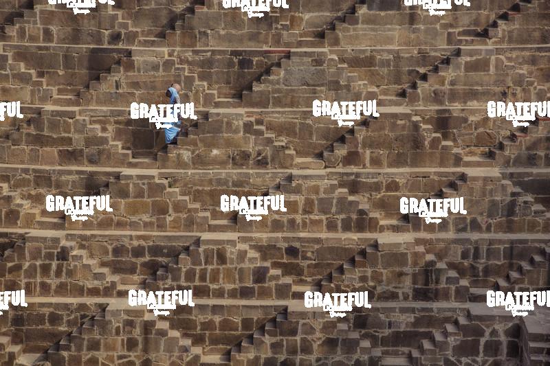 Woman with blue Sari walking to get water in the Chand Baori Step Well in India