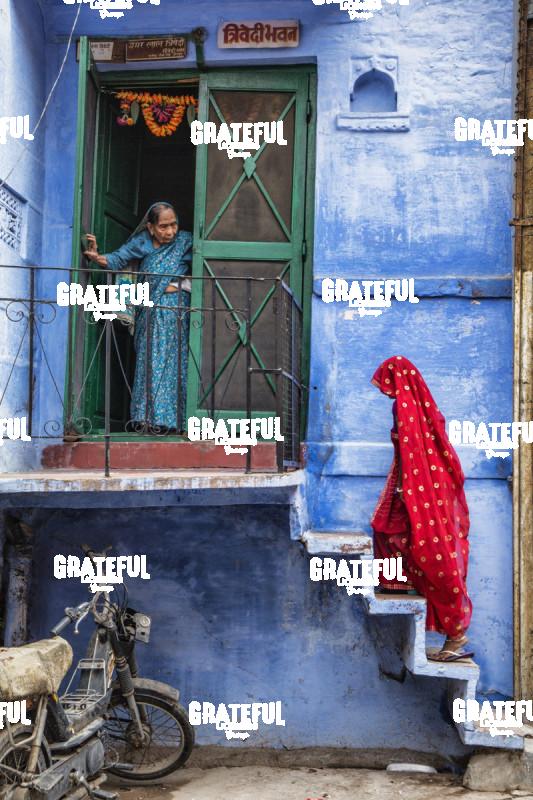 Woman with red Sari walking up steps in the blue city of Jodphur, India